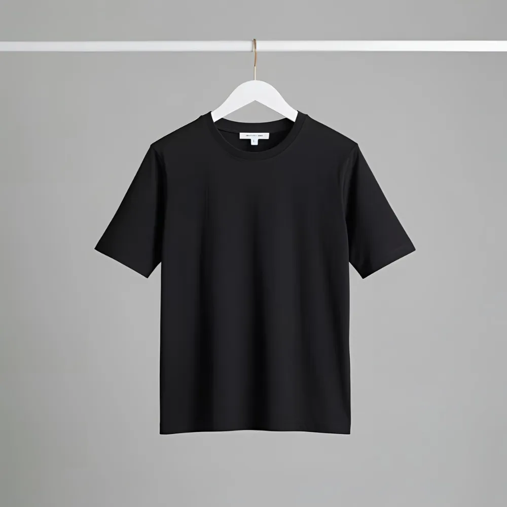 Essential black t-shirt hanging on a white hanger in a studio setting.
